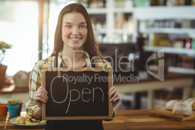 Smiling waitress showing chalkboard with open sign