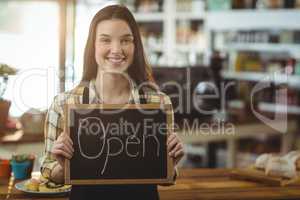 Smiling waitress showing chalkboard with open sign