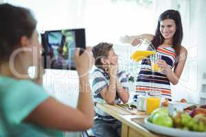 Girl clicking a photo of mother and brother from digital tablet