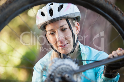 Female mountain biker examining wheel of her bicycle