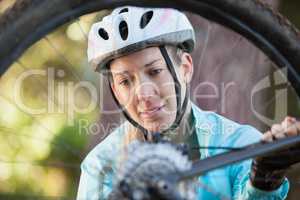 Female mountain biker examining wheel of her bicycle
