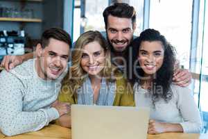 Smiling friends sitting with arm around in cafÃ?Â©