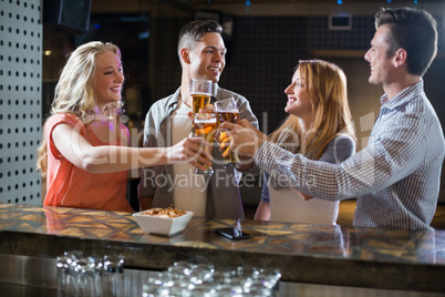 Friends toasting glasses of beer at bar counter