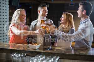 Friends toasting glasses of beer at bar counter