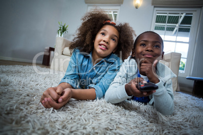Children holding remote while lying on the floor