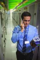 Technicians talking on mobile phone while analyzing server