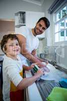 Son helping father in washing utensils