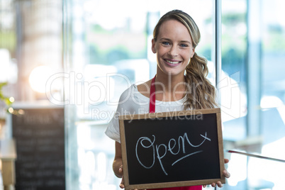 Smiling waitress showing slate with open sign