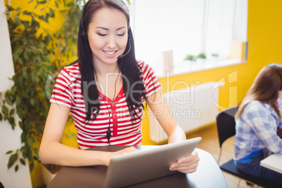 Happy beautiful executive using tablet at creative office