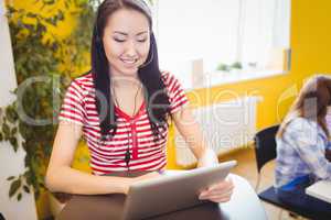 Happy beautiful executive using tablet at creative office