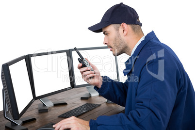 Security officer talking on walkie-talkie while looking at computer monitors