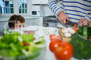 Boy looking while father chopping vegetables
