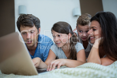 Happy family using laptop in bedroom