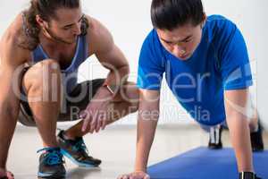 Fitness instructor helping fitness man with push-up