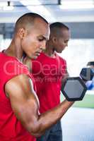 Man exercising with dumbbells against mirror