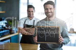 Man holding slate with open sign board in cafÃ?Â©