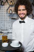 Waiter holding tray of beer glass and tea cup