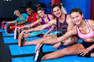 Portrait of smiling people doing stretching exercise in gym