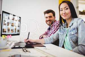 Smiling business people with graphic tablet at desk