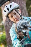 Female mountain biker examining wheel of her bicycle