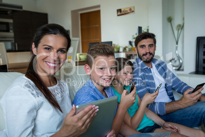 Family using laptop and mobile phone in living room at home