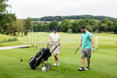 Male instructor assisting woman in learning golf