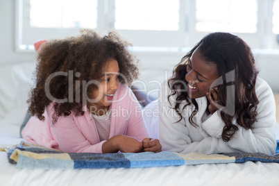 Portrait of mother and daughter lying on bed