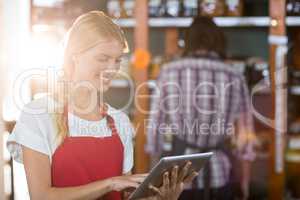 Female staff using digital tablet in supermarket