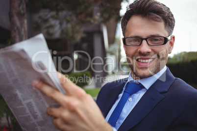 Portrait of handsome businessman reading newspaper