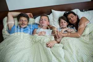Family sleeping together in bedroom