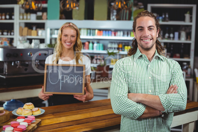 Smiling waitress standing with customer holding chalkboard with open sign