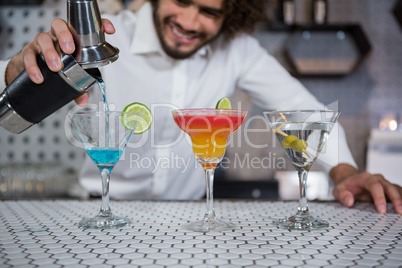 Bartender pouring cocktail into glasses
