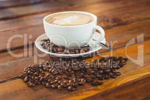 Cappuccino with coffee beans on table