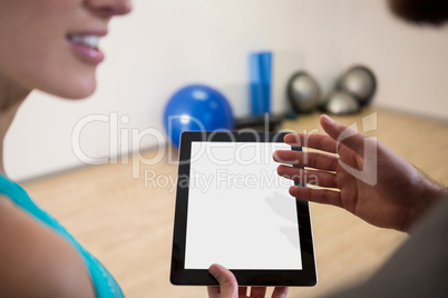 Fitness trainer showing digital tablet to woman