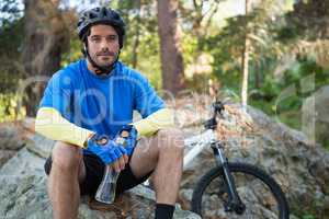 Portrait of male mountain holding water bottle and relaxing on a rock