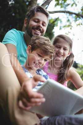 Father and kids using digital tablet in garden