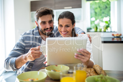 Couple using digital tablet while having breakfast