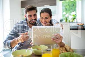 Couple using digital tablet while having breakfast