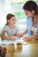 Smiling mother and daughter drawing together
