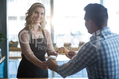 Waitress serving a cup of coffee and croissant to customer