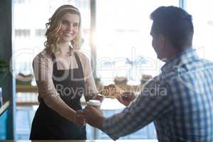 Waitress serving a cup of coffee and croissant to customer