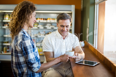 Smiling woman offering a cup of coffee to man