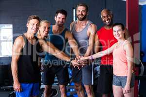 Portrait of smiling friends putting hands together in gym