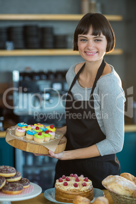 Portrait of waitress holding cup cake on tray in cafÃ?Â©