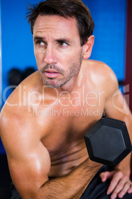 Shirtless athlete holding dumbbell in gym