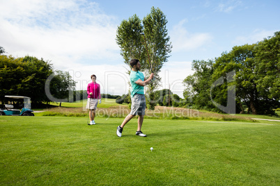 Male instructor assisting woman in learning golf