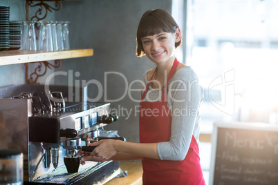 Smiling waitress making cup of coffee in cafe