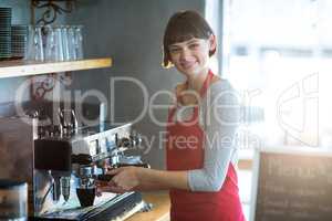 Smiling waitress making cup of coffee in cafe