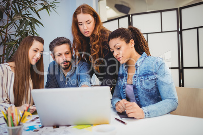 Businesswoman discussing with coworkers at desk