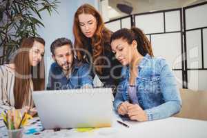 Businesswoman discussing with coworkers at desk